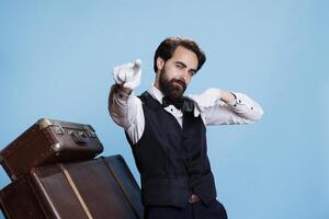 Smiling hotel concierge with gloves posing on camera, dancing with confidence and funky moves. Trendy stylish happy doorman fooling around and being silly in studio, groovy porter. photo