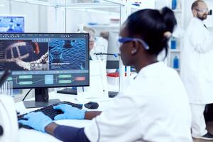 Multiethnic researcher team doing investigation in modern facility. African healthcare scientist in biochemistry laboratory wearing sterile equipment. photo