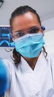 pov de paciente en un dental clínica sentado en cirugía silla mientras profesional dentista trabajando con guantes durante examen en moderno clínica utilizando esterilizado instrumentos foto