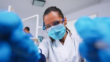 pov de paciente en un dental clínica sentado en cirugía silla mientras profesional dentista trabajando con guantes durante examen en moderno clínica utilizando esterilizado instrumentos foto