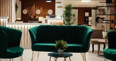 Crane down shot of welcoming rustic hospitality industry lobby interior filled with plants, waiting for guests. Empty cozy stylish hotel check in reception desk ready for arriving tourists photo