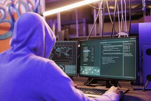 Criminal launching malicious software on computer screen for phishing attack. Internet scammer planning online fraud and coding malicious software in abandoned warehouse at night photo