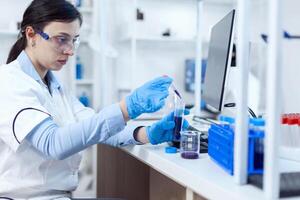 Woman scientist in lab during clinic experiement taking sample of genetic material using pipette. Chemistry researcher in sterile laboratory using modern technology to test microbiology liquid. photo