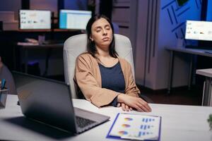 Workaholic freelancer sleeping in the course of deadline project in empty office. Employee falling asleep while working late at night alone in the office for important company project. photo