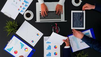 High angle view of business team working with financial reports at corporate office table analysing annual data planning next project. Manager sitting in conference room using modern technology. photo