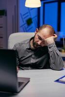 empresario dormido en empresa oficina debido a trabajar demasiado. trabajador obsesivo empleado que cae dormido porque de trabajando tarde a noche solo en el oficina para importante empresa proyecto. foto