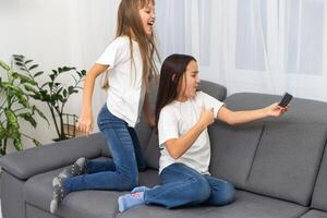 Happy schoolgirl lying near her friend and using new smartphone for chat photo