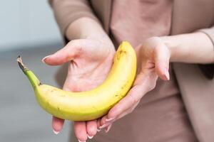 Fresh banana in a female hand isolated on white photo