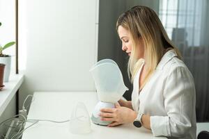 Young woman doing inhalation with a medical vaporizer nebulizer machine on black background photo