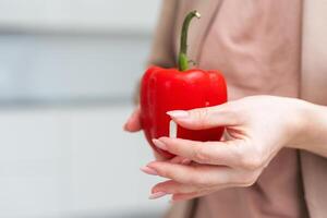 Whole paprika or red sweet pepper in hand isolated on white background with a pill. Human hand holding bell pepper or bulgarian pepper photo