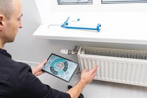 The technician checking the heating system in the boiler room with tablet in hand photo