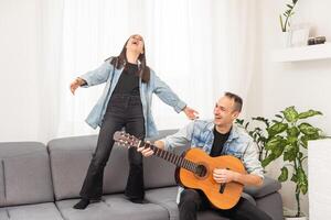 smiling father showing daughter how to play barre chord photo