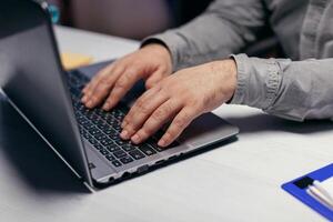 Close up of entrepreneur using laptop computer to finish project. . Male hands typing on laptop keyboard in office. Business, working from home, studying online concept photo