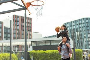 contento padre y adolescente hija fuera de a baloncesto corte. foto