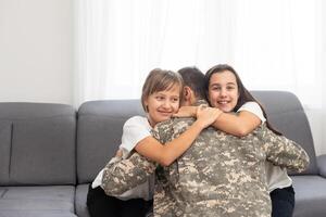 contento positivo sonriente soldado hombre en camuflaje sentado con su hija en sofá, mirando cómo su niño crecido cuando él estaba en ejército, volviendo hogar desde guerra. foto