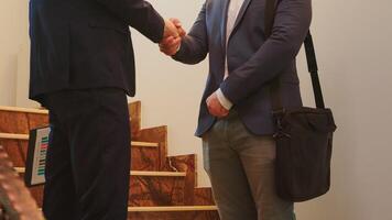 Business man partners executives shaking hands on stairs of office building while talking. Group of professional successful businesspeople in suit working together in modern financial workplace. photo