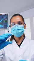 Dentist preparing anesthesia before tooth surgery, holding syringe with serum, pov patient. Doctor and nurse working in modern orthodontic office wearing protection mask and gloves photo