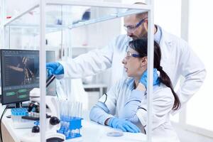 Determined professional scientists wearing uniform working with assitant at workplace. Team of researchers doing pharmacology engineering in sterile laboratory for healthcare industry. photo