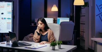 retrato de de estresado a trabajo haciendo tiempo extraordinario a completar importante tarea. empleado que cae dormido mientras trabajando tarde a noche solo en el oficina para importante empresa proyecto. foto