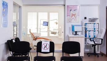 Waiting room in clinic with nobody in it, front office with new normal having sign on chair for social distance in coronavirus pandemic. Empty stomatology reception during covid-19 epidemic. photo