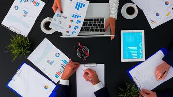 Directly above shot of businesspeople sitting at office desk and discussing financial documents using digital devices. Teamworkers planning in conference room on copy space, flat lay concept. photo