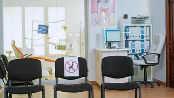 Dental clinic reception with nobody in it modern equipped with signs on chairs for social distance during global pandemic. Empty stomatology reception with new normal in covid-19 epidemic. photo