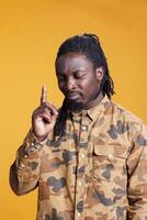 Concentrated man brainstorming ideas to find solution, taking thoughts into consideration while posing over yellow background in studio. Uncertain young adult contemplating about serious problem. photo