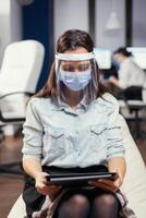 Woman entrepreneur wearing face mask against covid19 as safety precaution. Multiethnic business team working respecting social distance during global pandemic with covid-19. photo