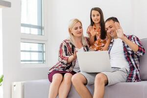 contento familia utilizando ordenador portátil juntos en sofá en casa foto