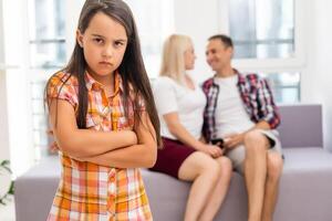 triste niña escuchando su padres mientras sentado en sofá a hogar foto