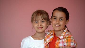 Portrait of two nice-looking attractive charming cute lovely friendly cheerful pre-teen girls isolated on pink pastel background photo