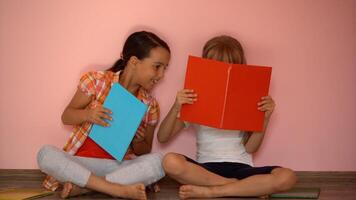 encantador pequeño muchachas son leyendo un libro. el concepto de educación. aislado en rosado antecedentes foto