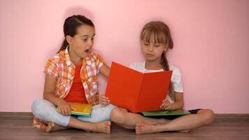 encantador pequeño muchachas son leyendo un libro. el concepto de educación. aislado en rosado antecedentes foto