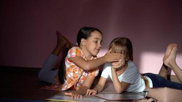 family, leisure and childhood concept - happy sisters lying on floor and doing homework at home photo