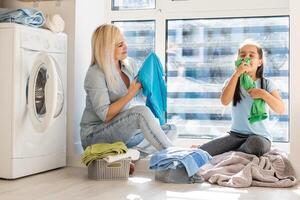 Young housewife and little girl doing laundry together photo