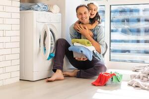 contento familia cargando ropa dentro Lavado máquina en hogar foto