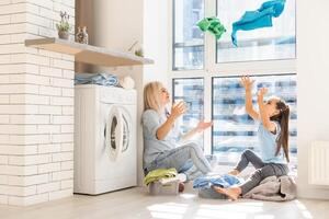 Young housewife and little girl doing laundry together photo