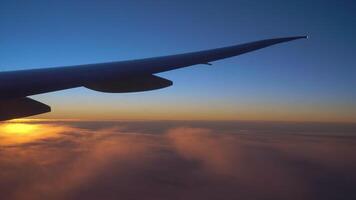 View from the airplane window of the wing, clouds and a beautiful sunset. video