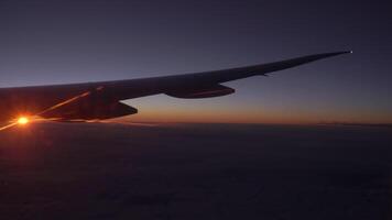 View from the airplane window of the wing, clouds and a beautiful sunset. video