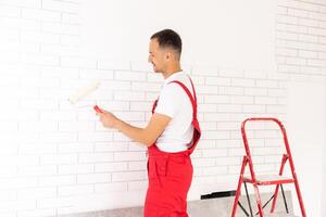 manos de el Maestro en guantes poner pegamento en un decorativo ladrillo antes de instalación en un pared foto