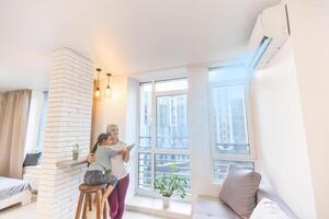 Mother in sportswear with daughter standing near the air conditioning photo