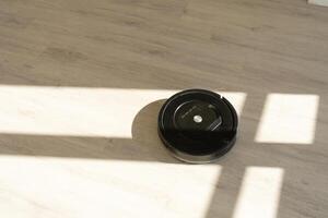 Robotic vacuum cleaner on laminate wood floor in living room photo