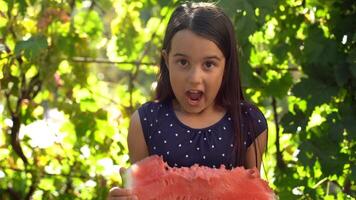 Happy child eating watermelon. Kid eat fruit outdoors. Little girl playing in the garden biting a slice of watermelon. photo