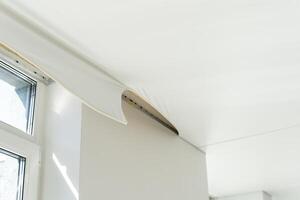 repairmen install stretch ceiling made of pvc vinyl film using a gas heat gun photo