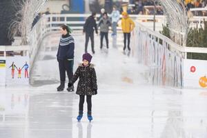 KYIV, UKRAINE - 1 January, 2023. Ice-skating people. People have fun in ice arena at the city ice rink. New Years holidays in city Kyiv. photo