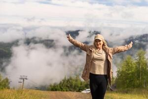 Beautiful young woman with backpack walking on meadow. Portrait of hiker girl outdoor photo