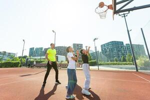 summer holidays, sport and people concept - happy family with ball playing on basketball playground photo