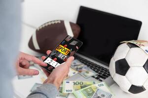 Man watching football match online broadcast on his laptop and holds smartphone with online gambling application and winning message. Bet concept photo