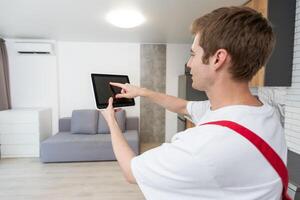 Worker with tablet computer checking alarm system indoors. photo