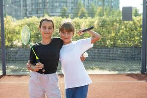 Two girls with badminton rackets on the football field. photo